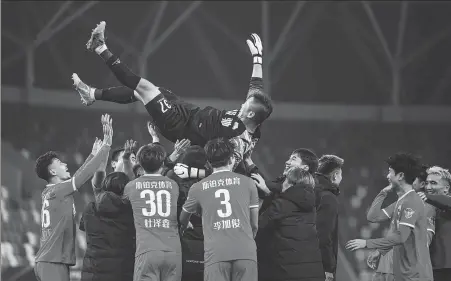  ?? XINHUA ?? Jingchuan Wenhui players throw their goalkeeper, Cui Tonghui, into the air following his heroics in the penalty shootout win that knocked Beijing Guo’an out of the CFA Cup last Thursday.