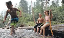  ??  ?? LANDON SILVA, 6, plays in the Merced River with Lincoln Montalvo, 6, and Ella Silva, 8. Undeterred by the smoke, they were staying at North Pines Campground.
