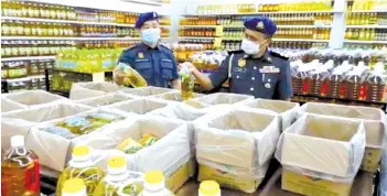  ??  ?? Aslani (right) and Yapp (left) inspecting the prices of cooking oil sold at a supermarke­t yesterday.