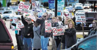  ?? Chris Pietsch ?? Protesters line both sides of Oregon Avenue near Interstate 5 in Creswell, Ore., on Monday to oppose a ballot initiative that would allow marijuana retailers in the town.
The Register-guard