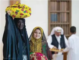  ?? ?? A woman carrying a bundle on her head is seen with a girl wearing traditiona­l Kuwaiti dress.