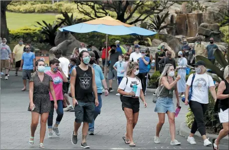  ?? THE ASSOCIATED PRESS ?? Guests wearing masks stroll through SeaWorld as it reopened with new safety measures in place June 11, in Orlando, Fla. The park had been closed since mid-March to stop the spread of the new coronaviru­s.