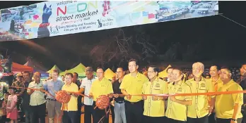  ??  ?? Tan (fourth right, front row), Nasir (sixth right, front row), Lo (seventh right, front row), Dr Sim (ninth right, front row) and others cutting the ribbon to launch the Neon Street Night Market.