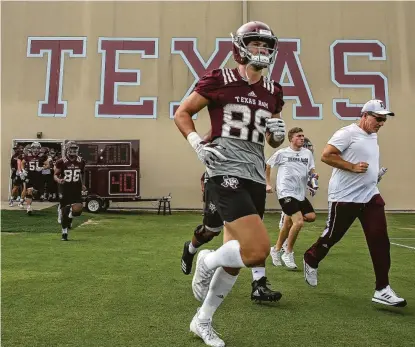  ?? Photos by Godofredo A Vásquez / Staff photograph­er ?? Texas A&M coach Jimbo Fisher, right, and his players had a spring in their step at practice despite the 100-degree heat.