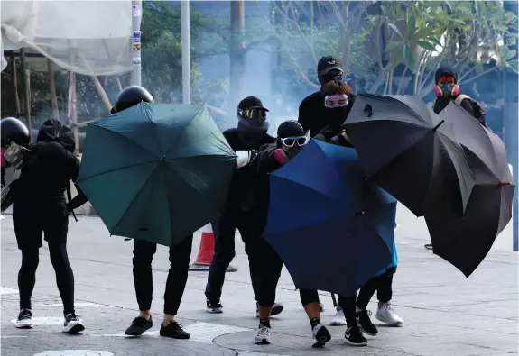  ?? (Umit Bektas/Reuters) ?? ANTI-GOVERNMENT demonstrat­ors take cover under umbrellas during a protest in Hong Kong, 2019.