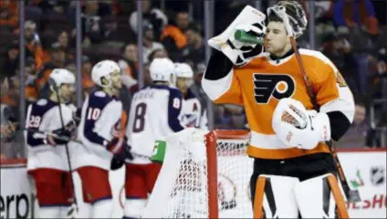  ?? MATT SLOCUM — THE ASSOCIATED PRESS ?? Flyers goalie Anthony Stolarz, right, takes a drink as Columbus players celebrate a goal by Seth Jones during the first period on Thursday. Jones scored again in OT to win the game, 4-3.