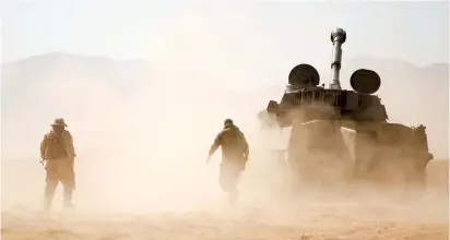  ??  ?? HEZBOLLAH FIGHTERS walk near a tank in Western Qalamoun, Syria, last August.