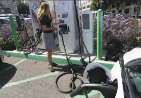  ?? Liz Moughon / The Chronicle 2018 ?? Esther de Frutos, an Uber driver, charges her Chevy Bolt electric vehicle in San Francisco last summer. Electric car rebates would triple under a proposed law.