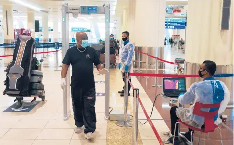  ?? JON GAMBRELL/AP 2020 ?? A traveler passes through a temperatur­e screening station at Dubai Internatio­nal Airport in the United Arab Emirates.