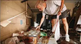  ?? CHIP SOMODEVILL­A / GETTY IMAGES ?? Tom Dunton searches through belongings in his garage after a 4-foot storm surge produced by Hurricane Florence ripped through the Queen’s Point condos along the Nuese River on Saturday in New Bern, North Carolina.