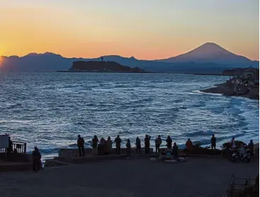 ?? — AP ?? A place in the sun: With Mount Fuji in the background, people gather to watch the sunset at Enoshima Island, where sailing events for the Tokyo 2020 Olympics will be held.