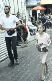  ??  ?? A Palestinia­n girl carries free wheat porridge distribute­d by Walid al-Hattab to help poor families during Ramadaan in Gaza City.