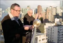  ?? The Canadian Press ?? Reverend Gary Paterson, right, and his partner Tim Stevenson clap and beat on a pot with a wooden spoon as part of a tribute to health care workers in Vancouver. Thousands of people in Vancouver’s west end have been going out on their balconies to applaud the front line heath care workers each night at 7pm.