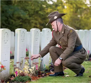  ??  ?? Private Allan Mildren places a poppy on the grave of his great great uncle Albert Mildren at the Strand Military Cemetery Ploegstree­rt, Belgium.