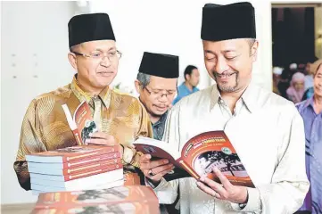  ??  ?? Mukhriz (right) having a closer look at the book written by Dr Muddathir Abd Al-Rahim. — Bernama photo