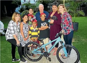  ??  ?? Te Taonga, wearing the black shirt was delighted to receive a new bike. He is pictured with members of the Trillian Trek team and his family.