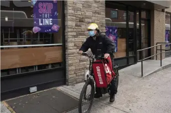  ?? Ap ?? UNDER A CAP: A delivery man for Grubhub sets out with a bag of food in New York.