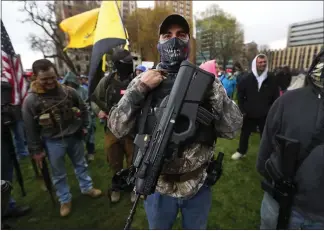  ?? PAUL SANCYA — THE ASSOCIATED PRESS ?? A protester carries his rifle at the state Capitol in Lansing, Michigan, on Thursday. Hoisting American flags and signs, protesters denounced Gov. Gretchen Whitmer’s stay-at-home order and business restrictio­ns.