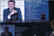  ?? JEAN-FRANCOIS BADIAS — THE ASSOCIATED PRESS ?? As French President Emmanuel Macron addresses the nation, local prefect Josiane Chevalier, right, watches in the local government building in Strasbourg, eastern France, on Wednesday.