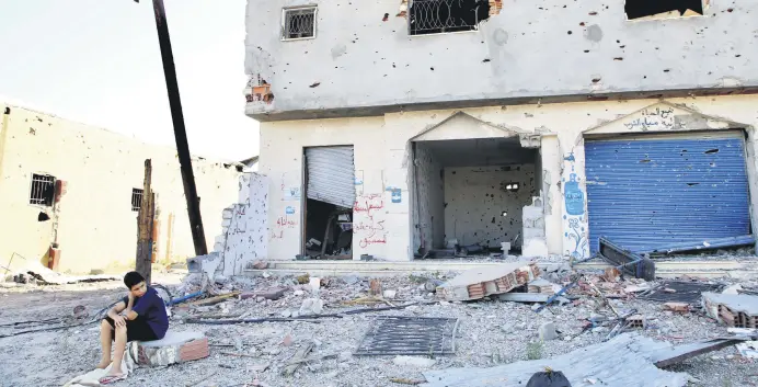  ??  ?? A child sits next to a building damaged by attacks carried out by forces loyal to putschist Gen. Khalifa Haftar, south of capital Tripoli, Libya, June 27, 2020.