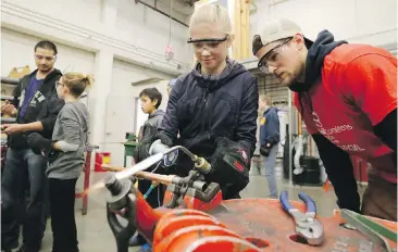  ??  ?? Rachael Ferguson from Spencer Middle school solders a metal tube with the help of Camosun student Sam Ballman, at a Camosun College event in 2015. Geoff Johnson writes that high schools can’t properly prepare students for the trades without up-to-date...