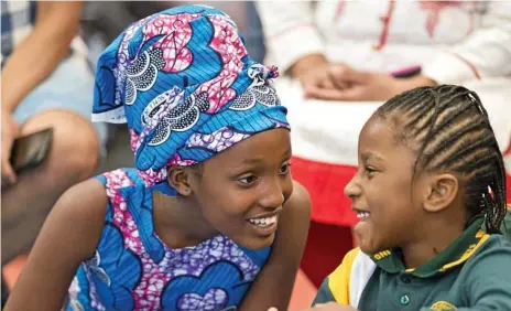  ?? Photos: Kevin Farmer ?? WE ARE ONE: Representi­ng Uganda, Wendy Poni (left) and Anna Kalondja react to fellow students saying hello in different languages during Harmony Day celebratio­ns at Darling Heights State School.