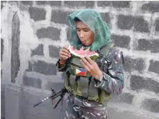  ?? — Reuters ?? A Philippine army soldier eats a watermelon while patrolling in Iligan on Saturday as government forces continue their assault against insurgents from the Maute group, who have taken over large parts of Marawi City.