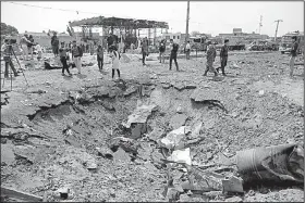  ?? AP/RAHMAT GUL ?? Journalist­s and security forces stand next to a crater Tuesday caused by Monday’s suicide bomb attack in the Green Village of Kabul, Afghanista­n.