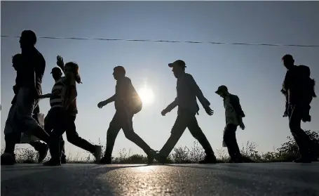  ?? PHOTO: REUTERS ?? Migrants walk along rail tracks as they arrive at a collection point in Hungary.