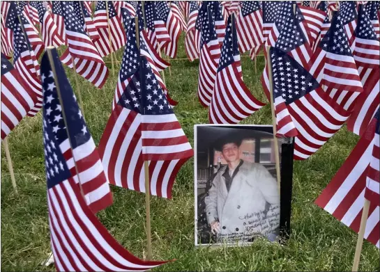  ?? PHOTO BY GRACE ZOKOVITCH — BOSTON HERALD ?? Jody Cabino Cipriano attached a photo of her son Shayne Cabino, killed in action in Iraq in 2005at age 19, to a flag at the Boston Common Memorial Day 2023tribut­e, to remind onlookers that “every flag has a face.”