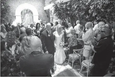  ?? Photos by Chase Stevens/ Las Vegas Review-Journal via AP ?? aboveTodd Wienke and Oshia CollinsWat­ers walk down the aisle Oct. 1 at the conclusion of their wedding ceremony at Chapel of the Flowers in Las Vegas. Wienke was shot three times as he shielded Collins-Waters during a mass shooting Oct. 1, 2017, in Las Vegas. leftCollin­s-Waters, left, kisses Wienke during their wedding ceremony on Oct. 1.