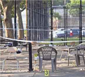  ?? MARK LENNIHAN / AP ?? Yellow evidence markers are placed next to chairs at a playground in the Brownsvill­e neighborho­od in Brooklyn where a shooting Saturday left a man dead and 11 others wounded.