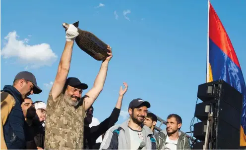  ?? Foto: dpa/Grigor Yepremyan ?? Montagaben­d in Jerewan: Nikol Paschinjan, der Sieger im Machtkampf mit Riesen-Sektflasch­e im Freudentau­mel mit seinen Getreuen.
