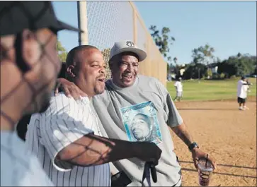  ?? Allen J. Schaben Los Angeles Times ?? BREWERS team member Garry “Twin” Dorton, in pinstripe jersey, hugs Twins fan Dutrell “Tutu” Perkins during the Crips softball league championsh­ip game in October. Dorton was fatally shot in South L.A. in July.