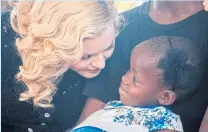  ??  ?? Madonna speaks to one of her two newly adopted daughters in Malawi.