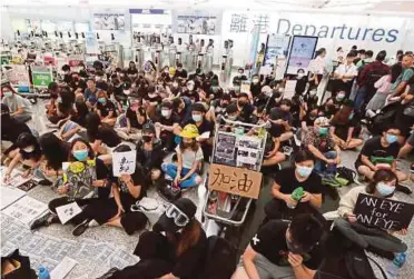  ?? REUTERS PIC ?? Antigovern­ment protesters sitting on the floor in front of security gates during a demonstrat­ion at Hong Kong Airport yesterday.