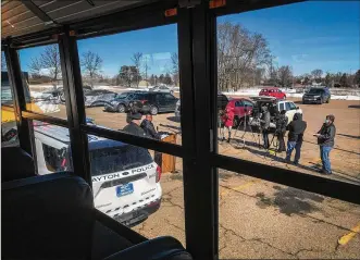  ?? STAFF ?? As seen from the inside of a bus, Dayton Public Schools’ chief of safety, Richard Wright II (at podium), and Dayton Police Lt. James Mullins (left) talk to the media Tuesday at Dunbar High School.