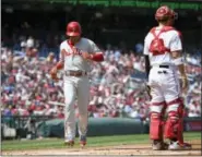  ?? NICK WASS — THE ASSOCIATED PRESS ?? Cesar Hernandez, left, comes home to score during the fourth inning Saturday. The second baseman added a game-winning two-run home run in the eighth inning as the Phillies doubled up the Nationals, 4-2, in Washington.