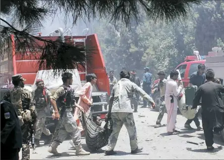  ?? Abdul Khaliq/Associated Press ?? Afghans carry an injured man Thursday after a suicide car bombing in Helmand province south of Kabul, Afghanista­n. The bomber struck outside a bank, targeting Afghan troops and government employees waiting to collect their salaries ahead of a major...