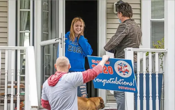  ?? Andrew Rush/Post-Gazette photos ?? Chartiers Valley High School teachers Craig Pisaneschi, left, and Mark Barzan talk to graduating senior Kayleen Carnes on her front porch as they deliver a care package Monday in Collier.