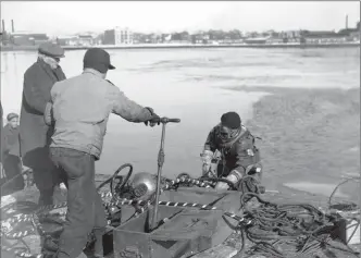  ?? Archives & Special Collection­s, University of Connecticu­t Library ?? Workers put down cable in the Quinnipiac River, from Southern New England Telephone Co. records held at the University of Connecticu­t Library, Storrs.