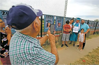  ?? PHOTOS BY LUIS SÁNCHEZ SATURNO THE NEW MEXICAN ?? Ruben Caraveo takes a picture Friday of his grandson, Alexey Caraveo, 18, with his mom, dad, brother and sister after Alexey collected his diploma at the Capital High School graduation ceremony.