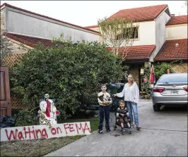  ?? SCOTT DALTON / THE NEW YORK TIMES ?? Rachel Roberts stands with her two sons, Troy, 10, and Harrison, 2, and their dog, Gizzy, at their home in Houston on Oct. 12. Roberts put up the skeleton lawn decoration with the sign that reads “Waiting on FEMA” after waiting three weeks for the...