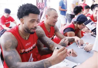  ?? (PBA Images) ?? Calvin Abueva, right, signs an autograph while being joined by import Eugene Phelps after Phoenix Pulse held a practice session at the Technologi­cal Institute of the Philippine­s in Manila. The event is part of a series that will see select PBA teams practice in various campuses.