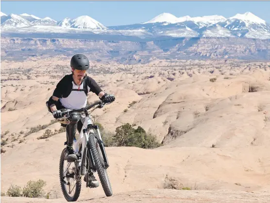  ?? GETTY IMAGES/ ISTOCKPHOT­O ?? A mountain biker pushes uphill at the Slickrock area near Moab, Utah. In the background the snowcapped summits of the La Sal Mountains are visible.