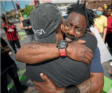  ?? AP ?? Former Minnesota Gopher and NFL football player Tyron Carter pleads with protesters not to tear up their city, as he hugs Tony L. Clark, foreground, at the site where George Floyd died Monday in the custody of Minneapoli­s police.