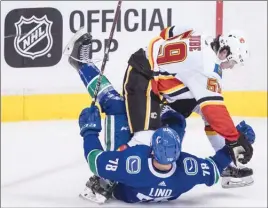  ?? The Canadian Press ?? Calgary Flames forward Dillon Dube ends up on top of Vancouver Canucks’ Kole Lind during second-period NHL preseason action in Vancouver on Wednesday night. The Canucks lost 4-1.