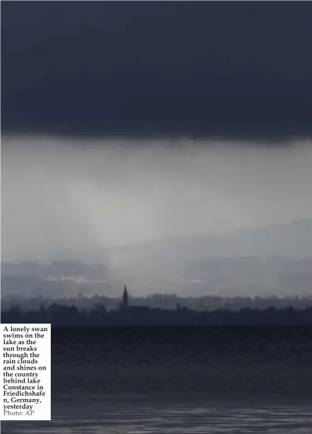  ??  ?? A lonely swan swims on the lake as the sun breaks through the rain clouds and shines on the country behind lake Constance in Friedichsh­afe n, Germany, yesterday Photo: AP