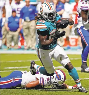  ?? WILFREDO LEE/ASSOCIATED PRESS ?? Dolphins running back Jay Ajayi charges past the Bills’ Lorenzo Alexander during Miami’s 28-25 win.