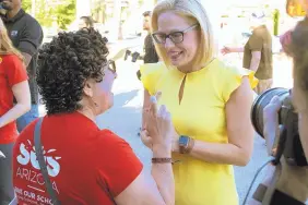  ?? BOB CHRISTIE/ASSOCIATED PRESS ?? A supporter crosses her fingers as she talks with Democratic U.S. Senate candidate Kyrsten Sinema in Phoenix on Saturday.